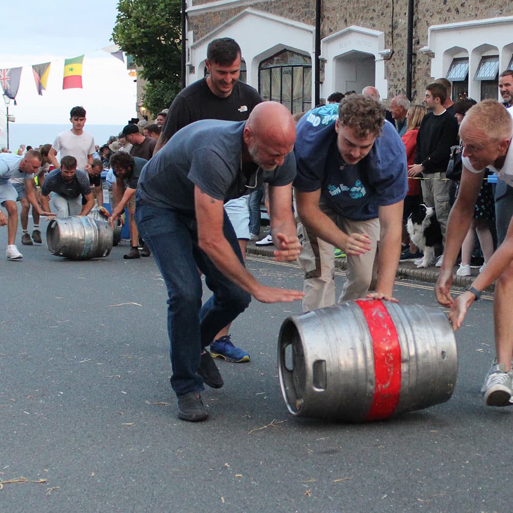 Teams racing barrels down Fore Street during Beer Regatta